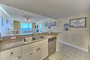 A modern kitchen with granite countertops, stainless steel appliances, and a view to the outside.