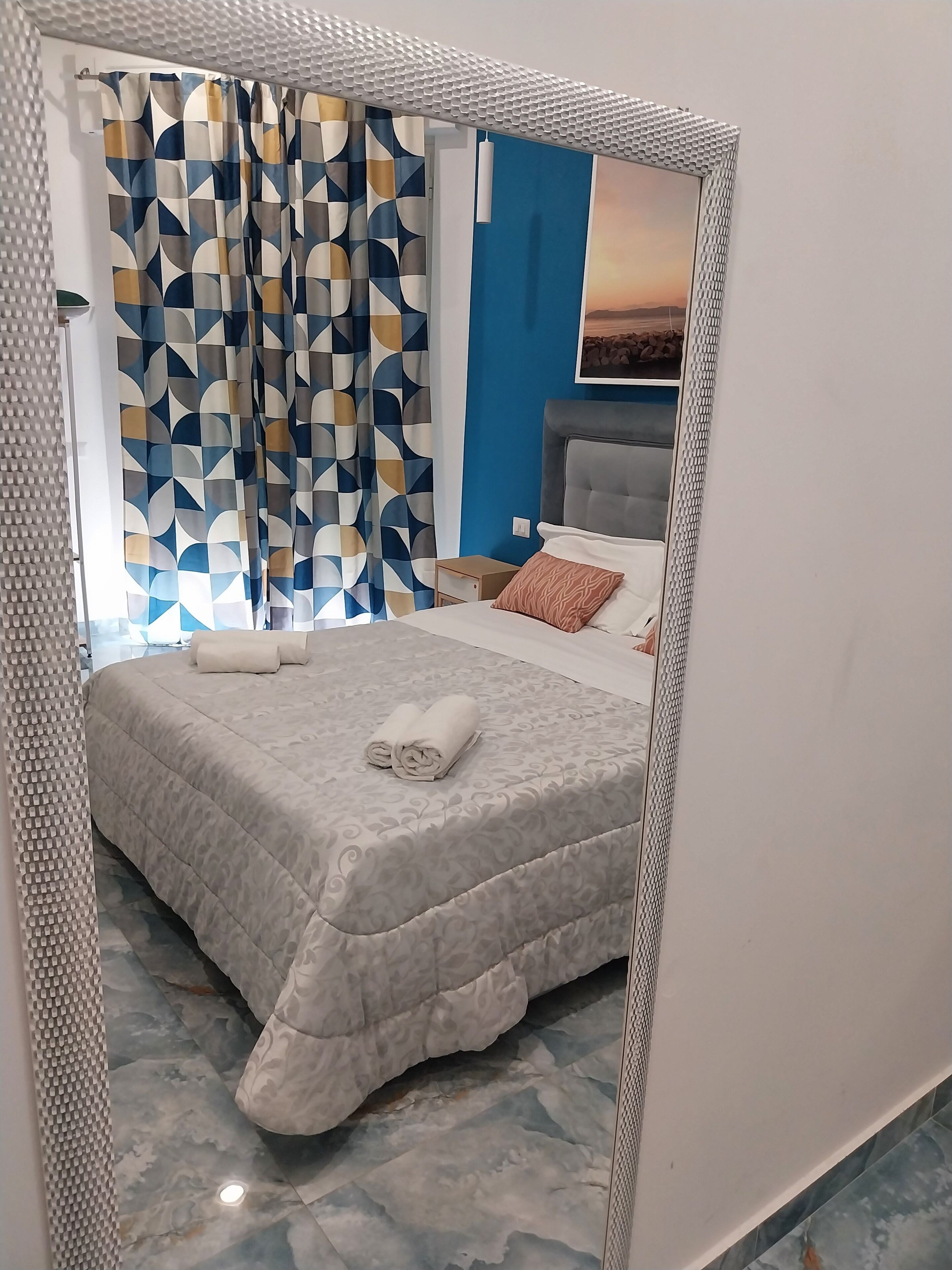 A modern bedroom with a bed, a nightstand, and a mirror.