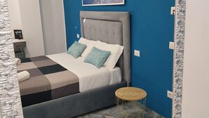 A bedroom with a bed, a bedside table, a chair, and a painting on the wall. - Attico Central Station Napoli (Naples)