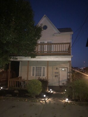 A two-story house with a front porch, a small garden, and a visible number '135' on the front door.