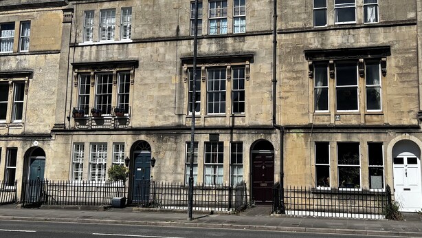 A row of traditional stone buildings with multiple windows and doors, featuring a classic architectural style. - Central Bath Georgian Rooms (Bath)