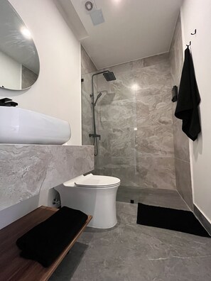 Ein modernes Badezimmer mit Toilette, Waschbecken mit Marmorplatte und Dusche mit Glasabtrennung.