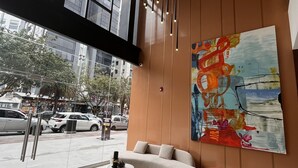 A modern lobby with a large abstract painting, a red chair, a sofa, and a marble floor.