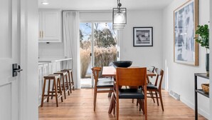 A dining area with wooden chairs and a table, white cabinets, and a large window with a view of trees. - Fireplace|Garage|Pets|King Bed! (Green Bay)