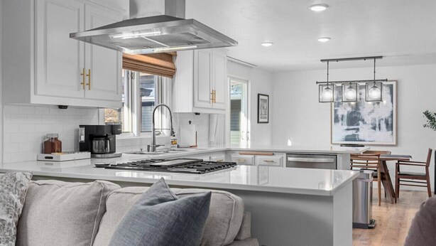 A modern kitchen with white cabinetry, a central island, a stainless steel range hood, and pendant lighting. - Fireplace|Garage|Pets|King Bed! (Green Bay)