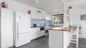 A modern kitchen with white cabinetry, a wooden countertop, and a built-in oven. - The Beach Box is a pet friendly rental (Manyana)