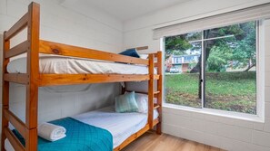 Une chambre avec des lits superposés, dont la fenêtre donne sur un quartier résidentiel.