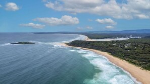 Un paysage côtier comprenant une plage, une zone boisée et un ciel dégagé.