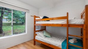 A bunk bed room with a window, white walls, and a view of greenery outside. - The Beach Box is a pet friendly rental (Manyana)