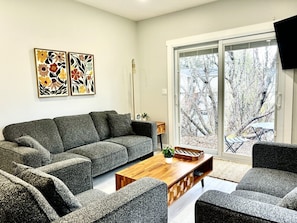 A modern living room with a sectional sofa, a wooden coffee table, and two abstract paintings on the wall.