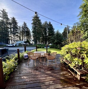 A wooden deck with outdoor furniture, surrounded by greenery and trees.