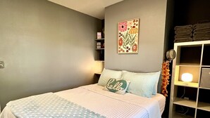 Een slaapkamer met een bed, een nachtkastje, een wandplank en een decoratief object aan de muur.