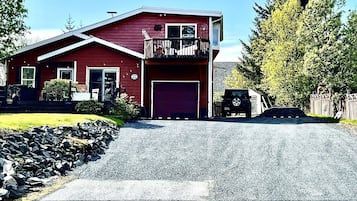 Une maison rouge à deux étages, avec un garage, un balcon et une allée.