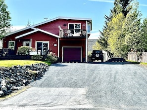 A two-story red house with a garage, a balcony, and a driveway.