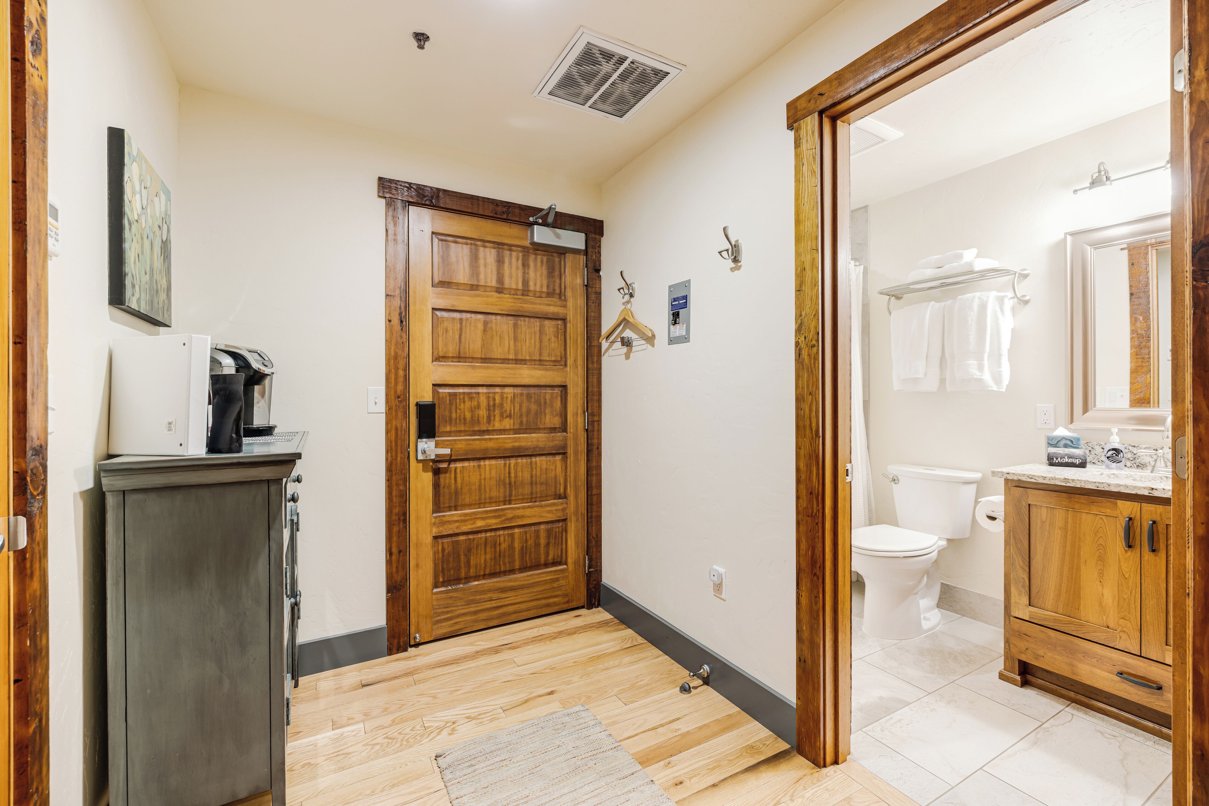 A hallway leading to a bathroom with a toilet, a sink, and a cabinet.