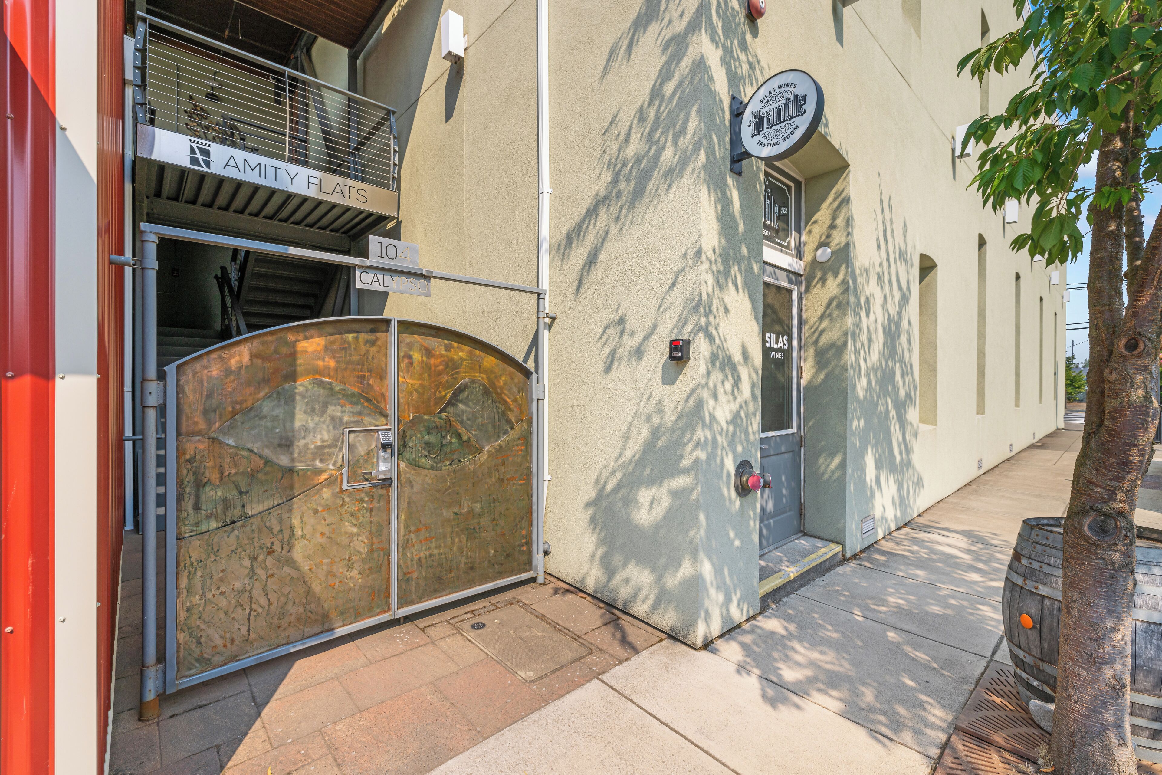 A building with a metal gate, a sign for 'AMITY FLATS', and a 'SILAS WINES' sign.