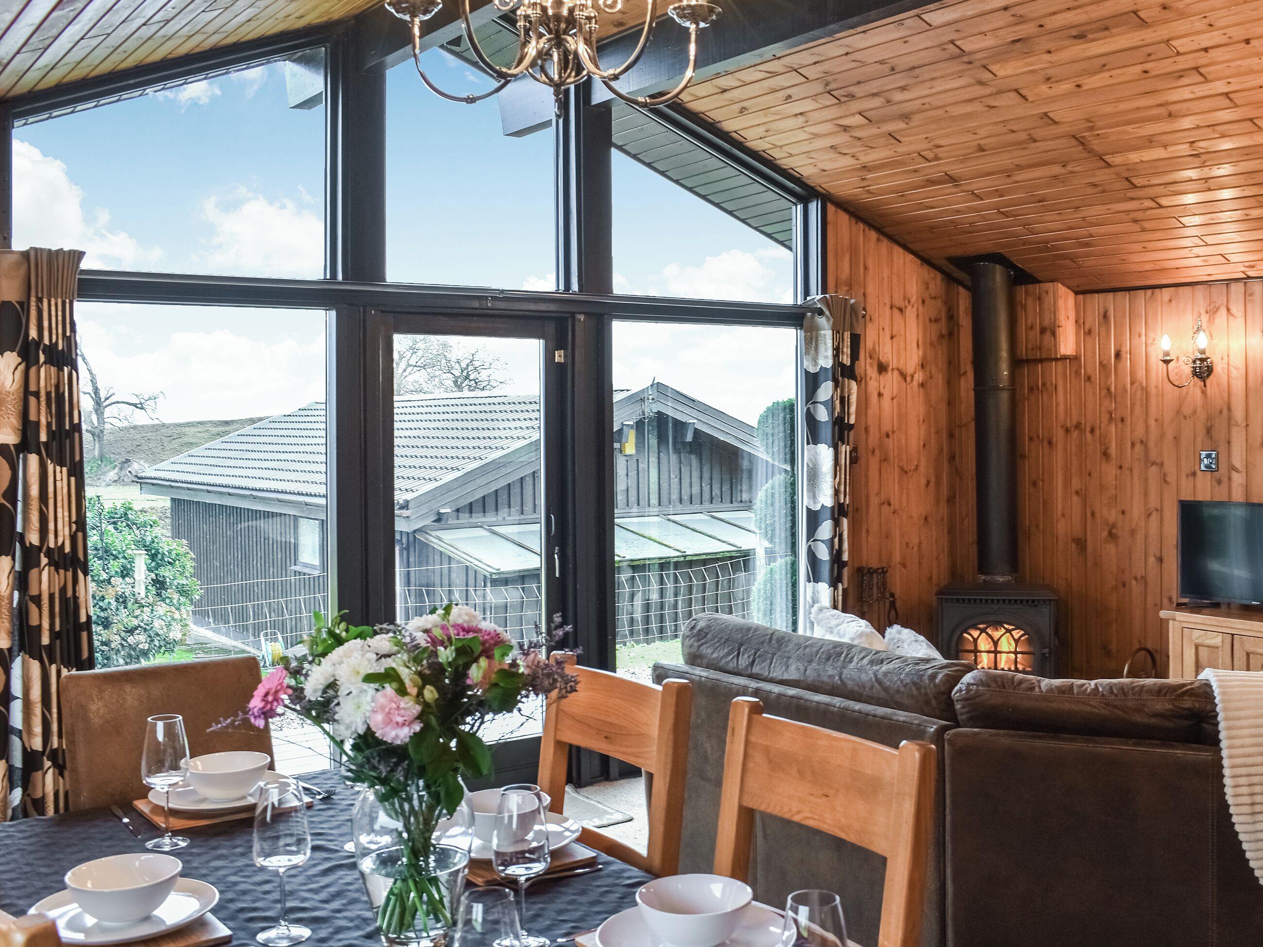 Un coin repas chaleureux avec une grande fenêtre, des murs en bois et une cheminée.