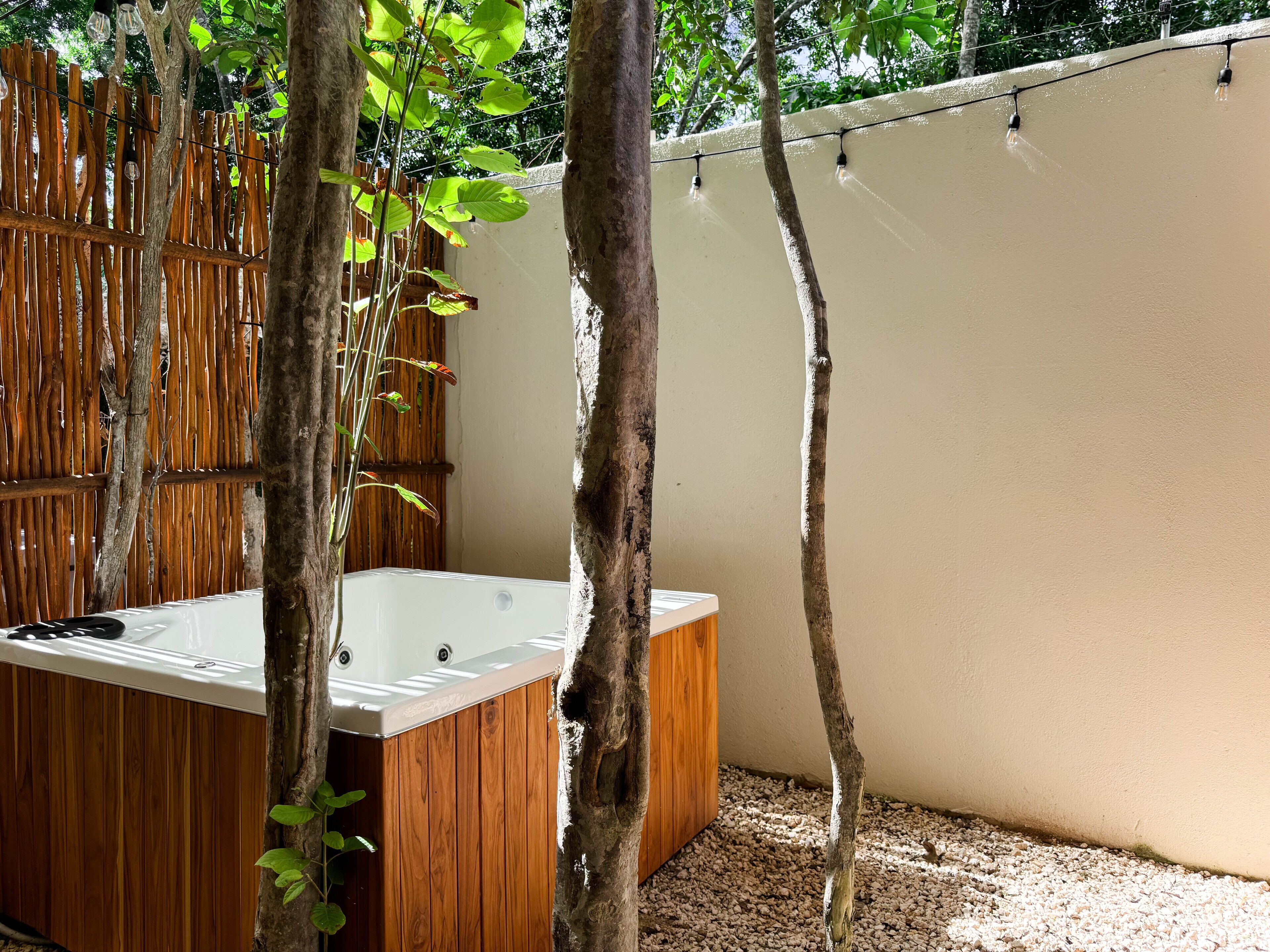 Un área de spa con hidromasaje, terraza de madera y valla de bambú.