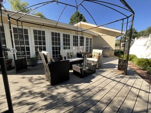 A covered patio with outdoor furniture, a grill, and a view of a house with large windows. - Spacious & quiet  Denver Home - 7bedroom, 5 bath & queen (Arvada)
