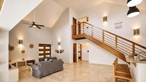 Amplia sala de estar con techos altos, una escalera de madera y una cocina moderna.