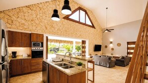 Una cocina con encimeras de granito, armarios de madera, horno empotrado y una isla grande con pileta.
