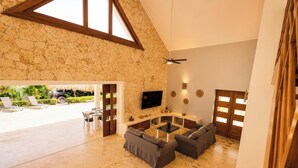 Amplia sala de estar con pared de piedra, televisor de pantalla plana y ventilador de techo.