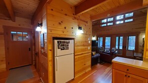 L’intérieur d’une cabane en bois comprend un espace cuisine, des murs en bois et de grandes fenêtres.