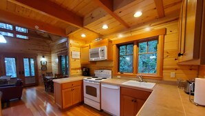 Une cuisine de style rustique, avec des murs en bois, une cuisinière, un four à micro-ondes et un évier.