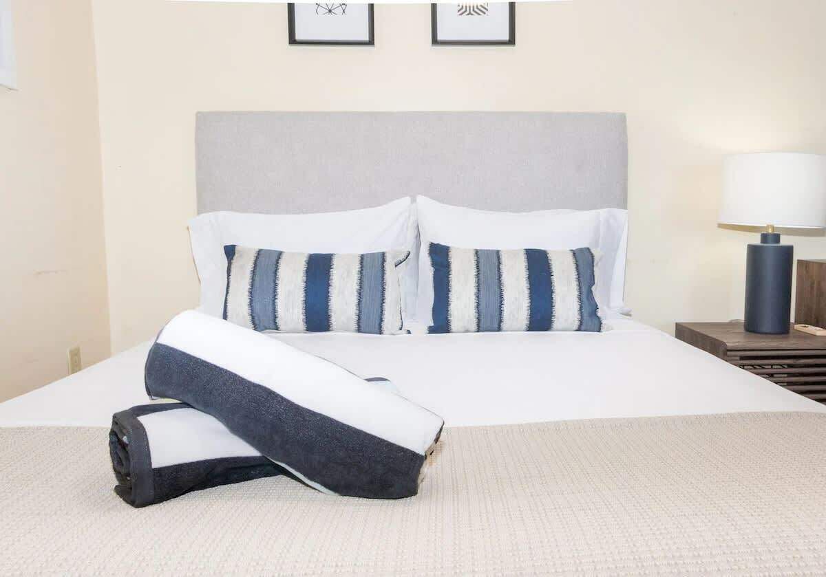 A neatly made bed with striped pillows and a rolled-up blanket.