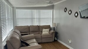 Una sala de estar con un sofá modular, una mesita y un televisor instalado en la pared.