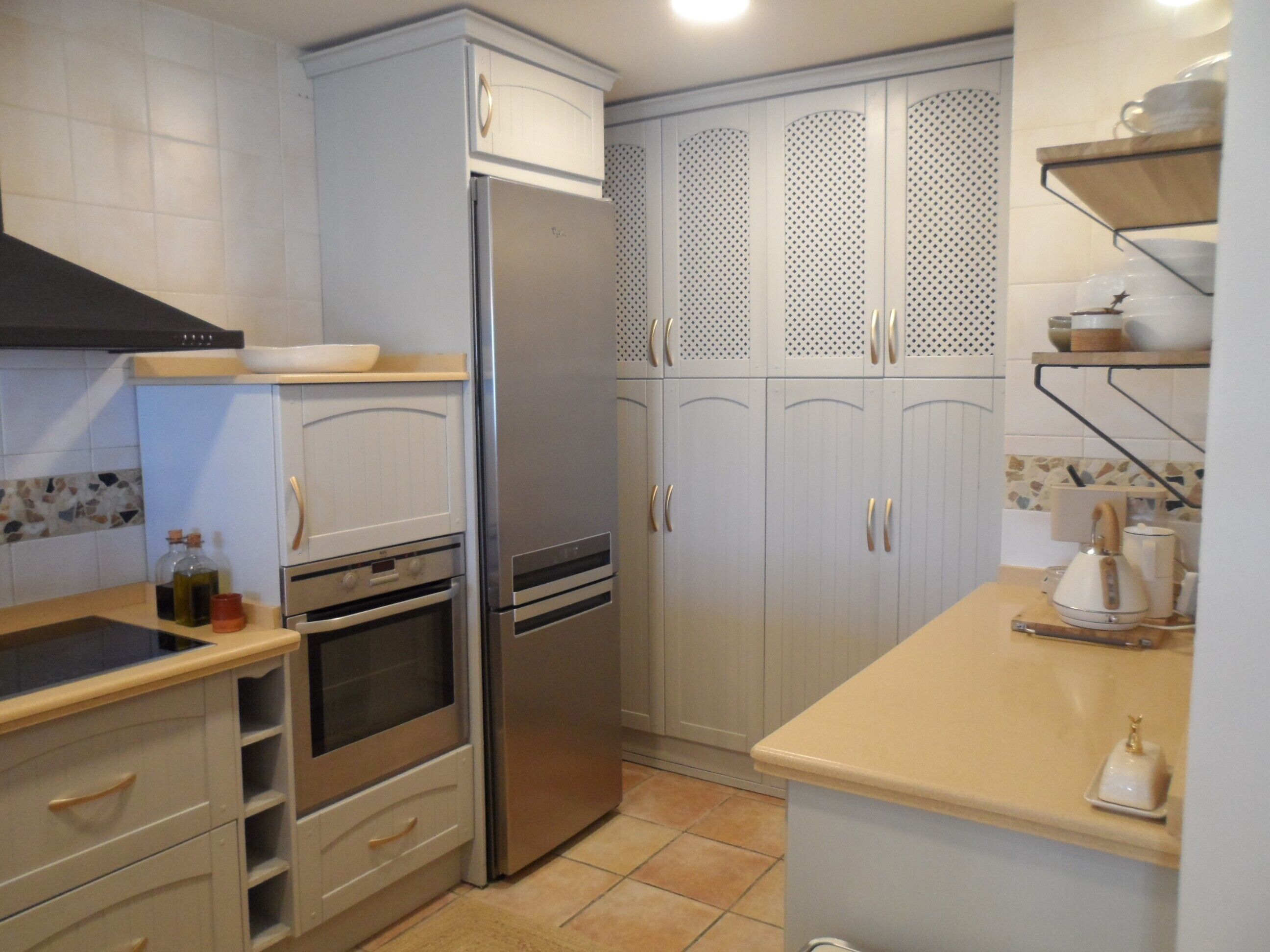 Una cocina con un refrigerador de acero inoxidable, horno empotrado y un lavamanos.