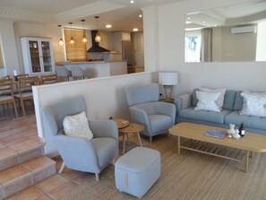 A modern living room with grey sofas, a wooden coffee table, and a kitchen in the background. - Villa 'Torre Del Mar' with Sea View, Wi-Fi and Air Conditioning (Salobreña)