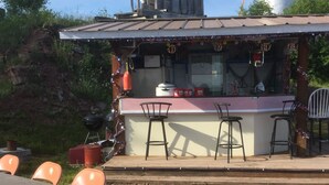 An outdoor bar area with a counter, bar stools, and a grill. - The Beachcomber at Dockside Resort - Near Bohemia and Trails (Lake Linden)