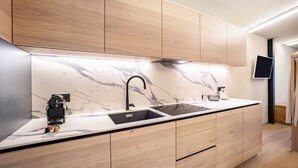 A modern kitchen with a marble backsplash, wooden cabinets, a black faucet, and a built-in TV. - Studio Apartment 'Avia Living Elisabeth' with Mountain View and Wi-Fi (Brunico)