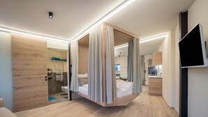 Une chambre d’hôtel moderne avec un lit suspendu, une télévision et un plancher en bois.