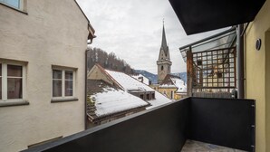 Un balcon donnant sur une église et sur des toits enneigés.