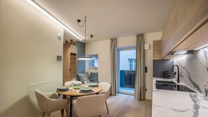 Un espace repas moderne avec une table ronde, quatre chaises et une vue sur un balcon.