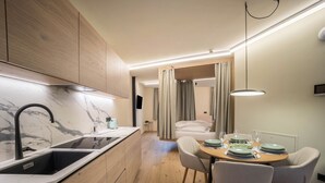 Une cuisine moderne dotée d’un plan de travail en marbre, de meubles en bois et d’un coin repas avec une table dressée pour quatre personnes.