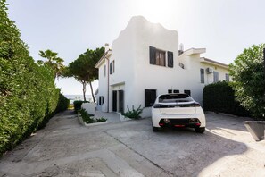 A white two-story house with a white car parked in the driveway.