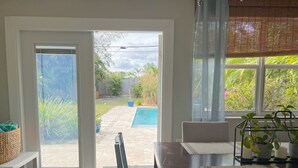 A dining area with a view of a backyard, including a pool and garden. - Lush Tropical Oasis! HEATED Pool, 1 mile to downtown, 2 miles to public beach (Lake Worth Beach)