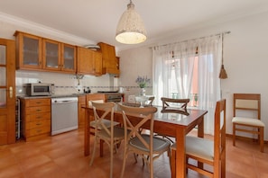 Una cocina con armarios de madera, lavavajillas, microondas y una mesa de comedor con sillas.