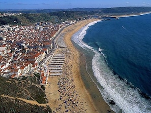 Vista aérea de una ciudad costera con playa, edificios y cielo despejado.