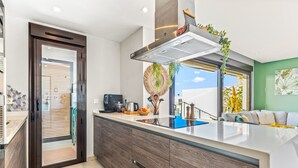 A modern kitchen with a built-in island, a coffee machine, and a view to the living area. - Apartment 'Casa Marysol' with Sea View, Wi-Fi and Air Conditioning (Orihuela)