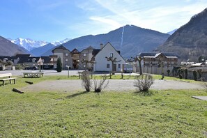 A residential area with houses, a paved courtyard, and mountains in the background.
