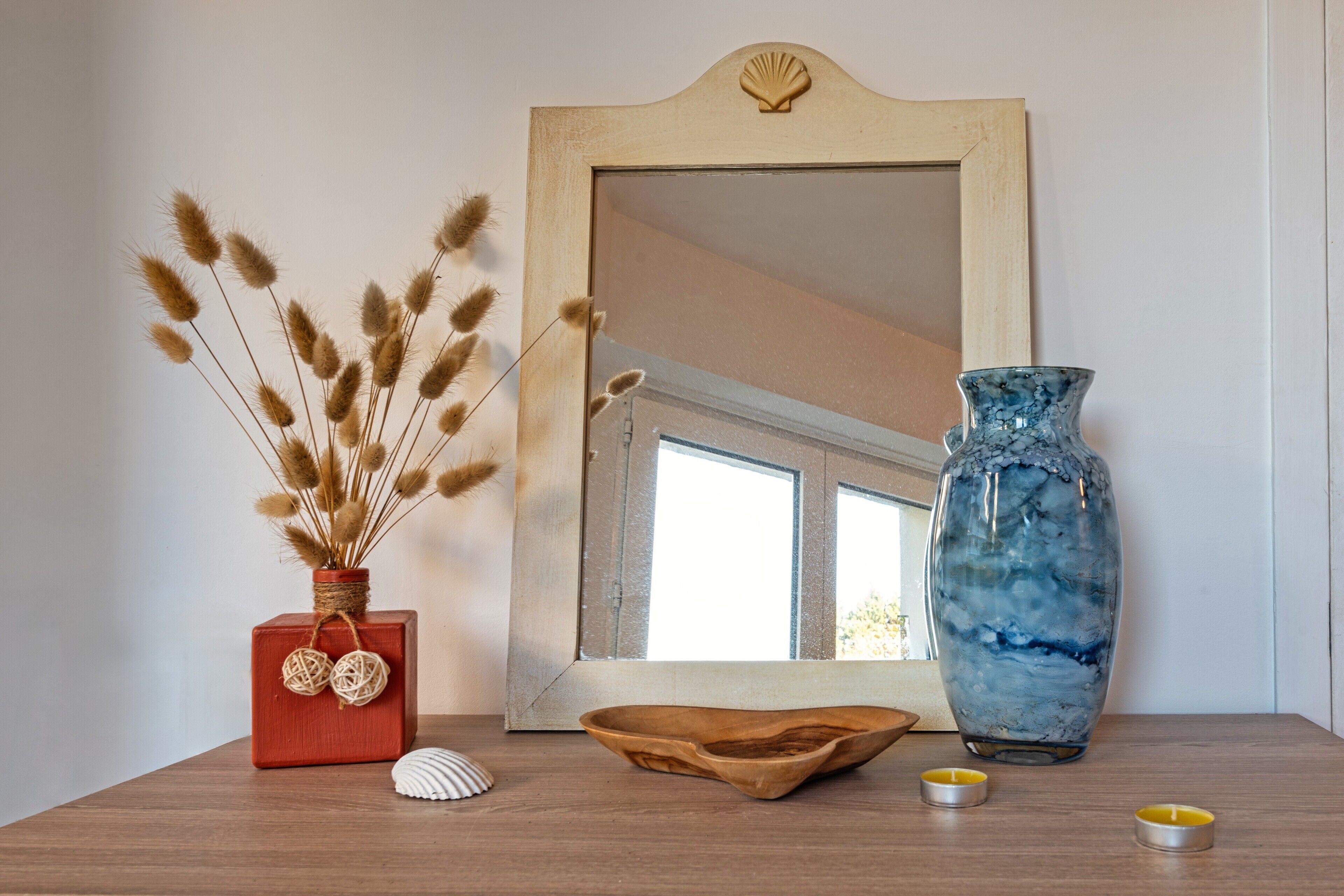 Ein Holztisch mit einer Vase, einem Spiegel und Dekorationselementen.