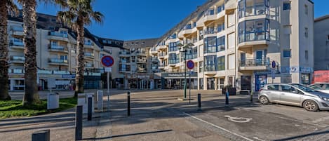 Ein mehrstöckiges Hotel mit Balkonen, Parkplätzen und Palmen.