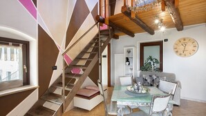 Eine Treppe mit Metallgeländer, ein Essbereich mit Tisch und Stühlen sowie eine Wanduhr.