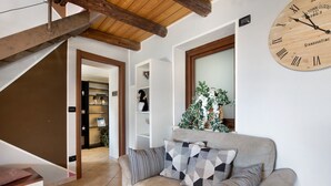 Ein Wohnzimmer mit einer Couch, einer Holzbalkendecke, einer Wanduhr und einer Treppe.
