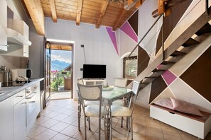 A modern kitchen with a dining area, a TV, and a staircase.