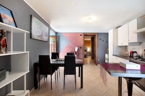 A dining area with a table and chairs, a kitchen with cabinets and appliances, and a hallway leading to another room. - Apartment 'Maison Bebe Terre Blanche' with Mountain View, Private Terrace and Wi-Fi (Pollein)
